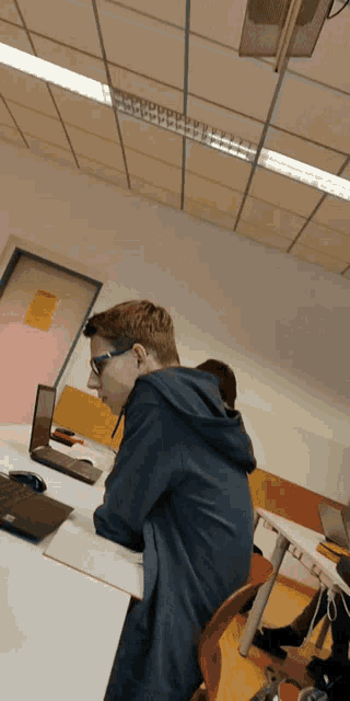 a young man sits at a desk with a laptop