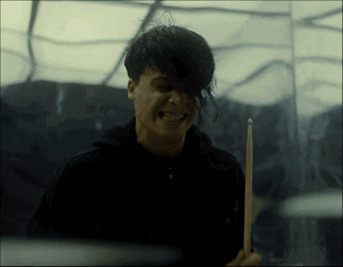 a man playing drums with his eyes closed and his mouth open