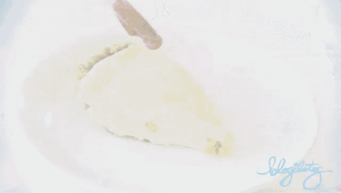 a slice of cheesecake with raspberry sauce being poured on top of it
