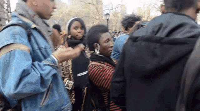 a man in a denim jacket is talking to a woman in a crowd