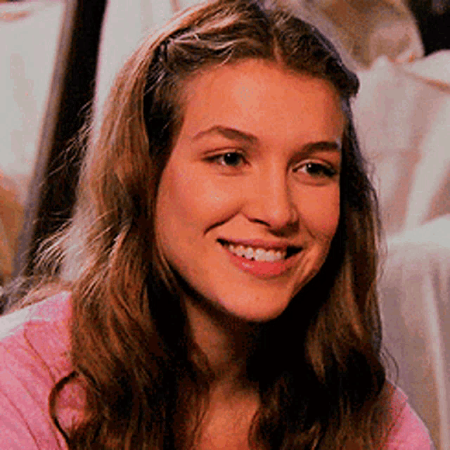 a close up of a woman 's face with a pink shirt on