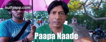 a man holding an umbrella with the words paapa naade written on it .