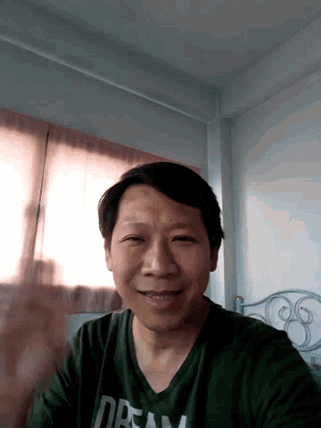 a man wearing a green shirt that says dream is smiling