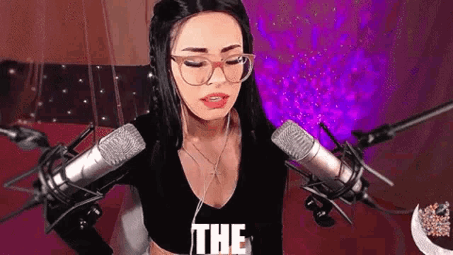 a woman wearing glasses and headphones is standing in front of a microphone and says the .