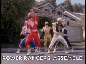 a group of power rangers are standing in front of a house and dancing .