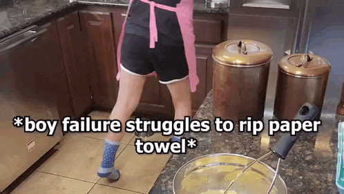 a woman in a pink apron is standing in a kitchen with the words boy failure struggles to rip paper towel