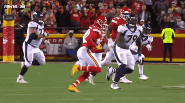 a group of football players are running on a field with a ball .