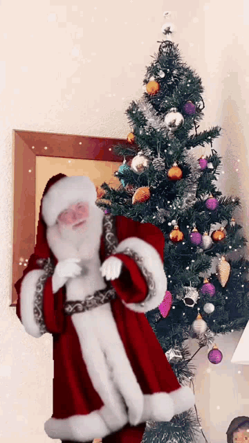 santa claus standing in front of a decorated christmas tree