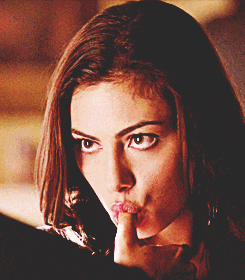 a close up of a woman with her finger on her lips