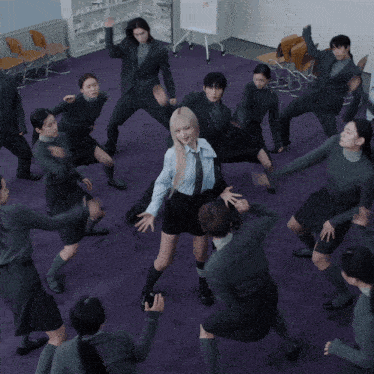 a group of people are dancing in a circle with a girl covering her face
