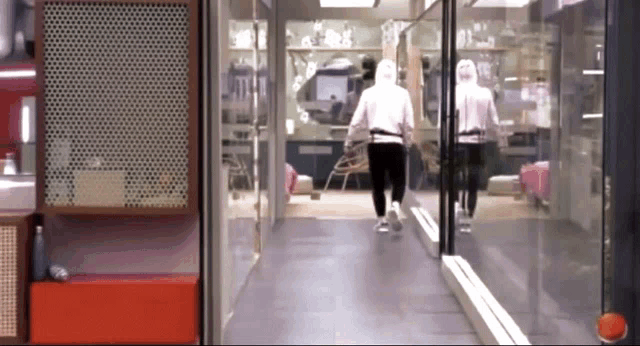 two people are walking down a hallway with a reflection of them in the mirror