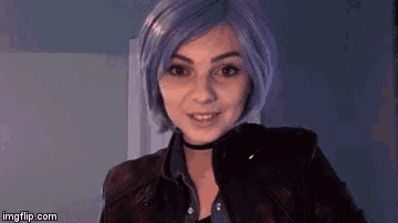 a woman with purple hair and a leather jacket is smiling .