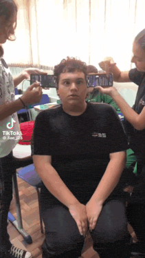 a group of people are taking a picture of a boy 's face with their cell phones