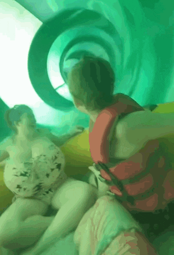 a group of people are riding down a water slide at a water park