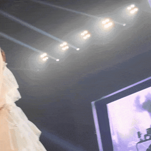 a woman in a white dress is standing in front of a screen with a purple background