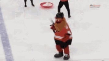 a person in a red and black hockey uniform is holding a stick on a rink .