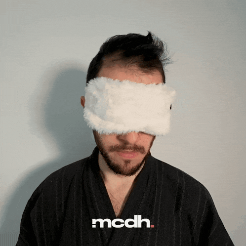 a man wearing a white eye mask with mcdh written on the bottom right