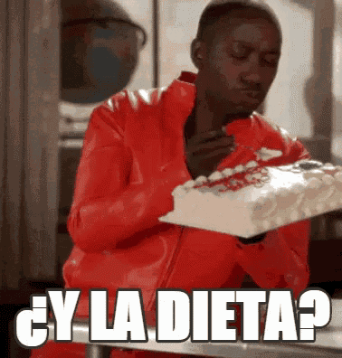 a man in a red jacket is sitting at a table eating a cake with the words " y la dieta " above him