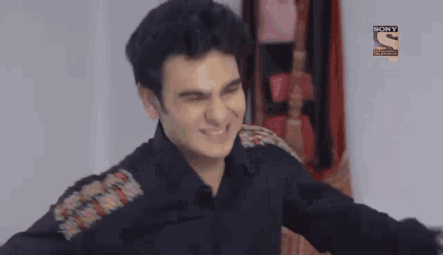 a man is making a funny face in front of a sign that says sony television hd .