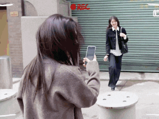 a woman taking a picture of another woman with a red rec sign in the corner