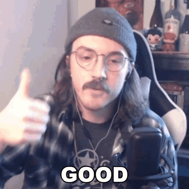 a man with a mustache and glasses is giving a thumbs up and the word good is on the bottom