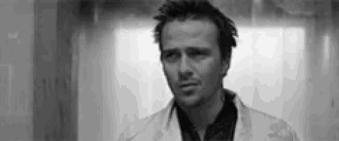 a black and white photo of a man in a lab coat looking at the camera .