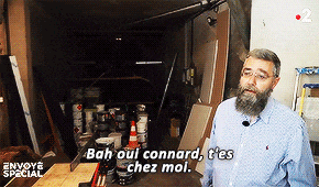 a man with a beard is standing in a garage and says bah oui connard t'es chez mol