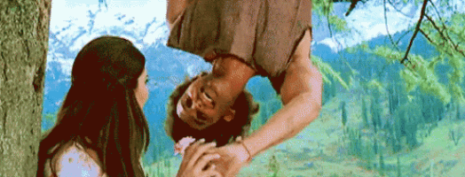 a man hanging upside down from a tree while a woman holds his hand .