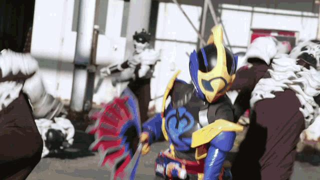a man in a blue and yellow costume is fighting a group of people .