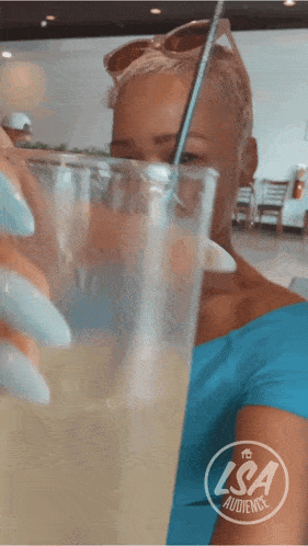 a woman in a blue shirt is drinking from a glass with a straw and a logo for lisa audience