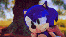 a person is holding a stuffed sonic the hedgehog in their hand .