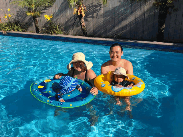a man and a woman are swimming in a pool with a baby in a float