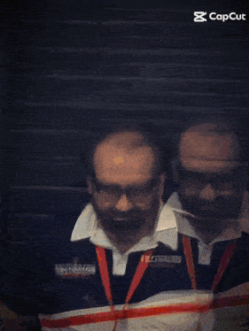 a man wearing glasses and a lanyard that says ' trolley ' on it is standing next to another man