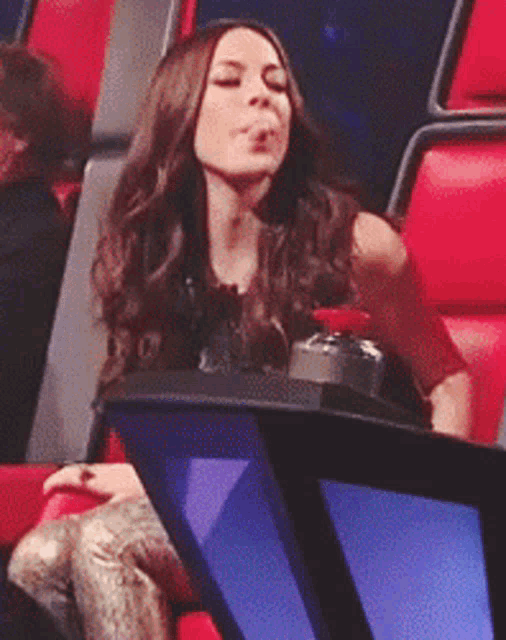 a woman is sitting in a chair with her eyes closed and her mouth open