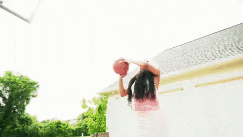 a woman is throwing a basketball in the air .