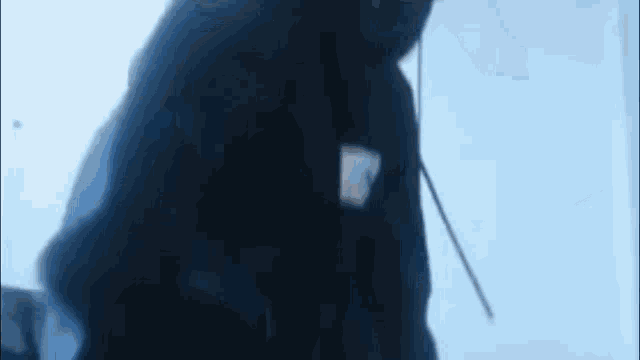 a man in a black hoodie is standing in front of a blue background .