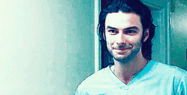 a man with long hair and a beard is wearing a blue shirt .