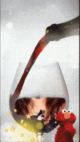 a bottle of wine is being poured into a wine glass with elmo standing next to it