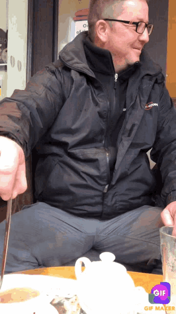 a man is sitting at a table with a gif maker app on his phone