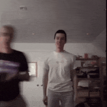 a man in a white t-shirt is standing next to a man in a black shirt