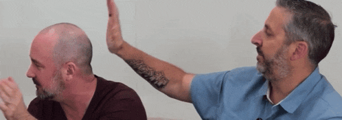a man with a tattoo on his arm is giving a high five to another man