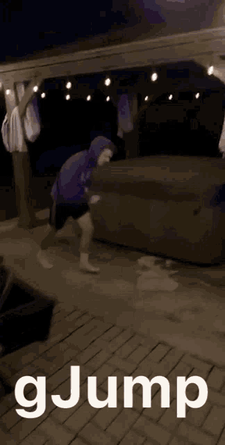 a man in a purple hoodie is jumping on a brick sidewalk