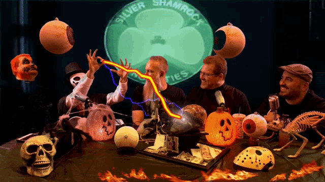 a group of men are sitting around a table with a shamrock logo in the background