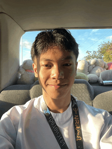 a young man in a car with a lanyard that says ' tp10h0rt ' on it
