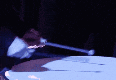 a person is playing a drum in a dark room with a blue light