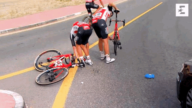 a cyclist with the number 28 on his shorts is standing next to another cyclist