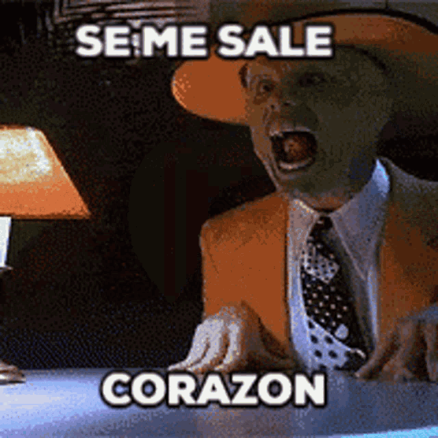 a man with a mask on his face is sitting at a table with the words se me sale corazon above him