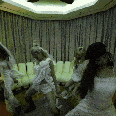a group of women in white dresses are dancing together