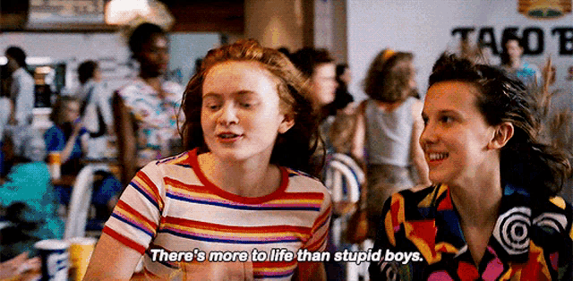 a couple of girls are sitting next to each other in a crowded restaurant .