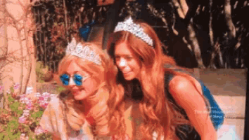 two women wearing tiaras are posing for a picture